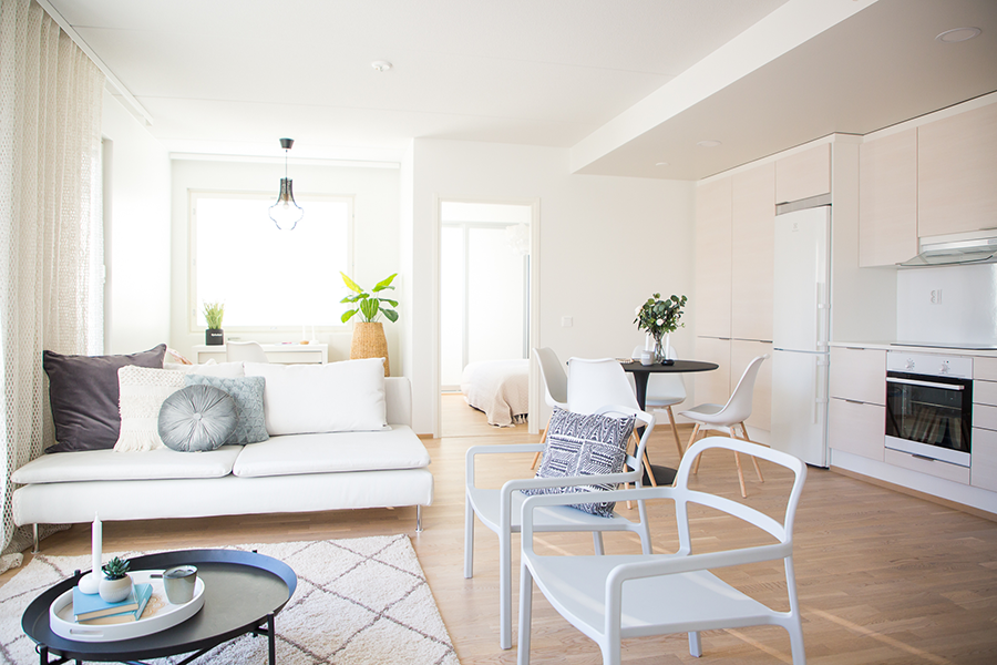 Olohuone skandinaaviseen tyyliin, jossa on valkoinen Ikean Söderhamn sohva, musta sohvapöytä ja musta Ikean Dockta ruokapöytä.